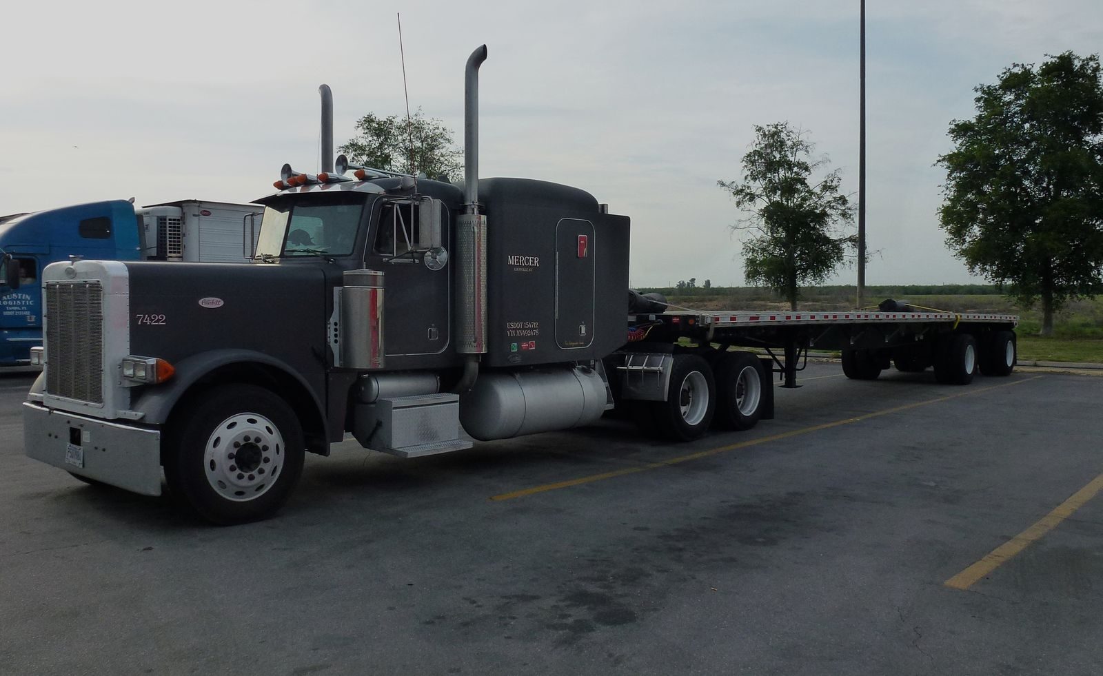 Flatbed semi trailer hooked to a Peterbilt tractor at a truck stop